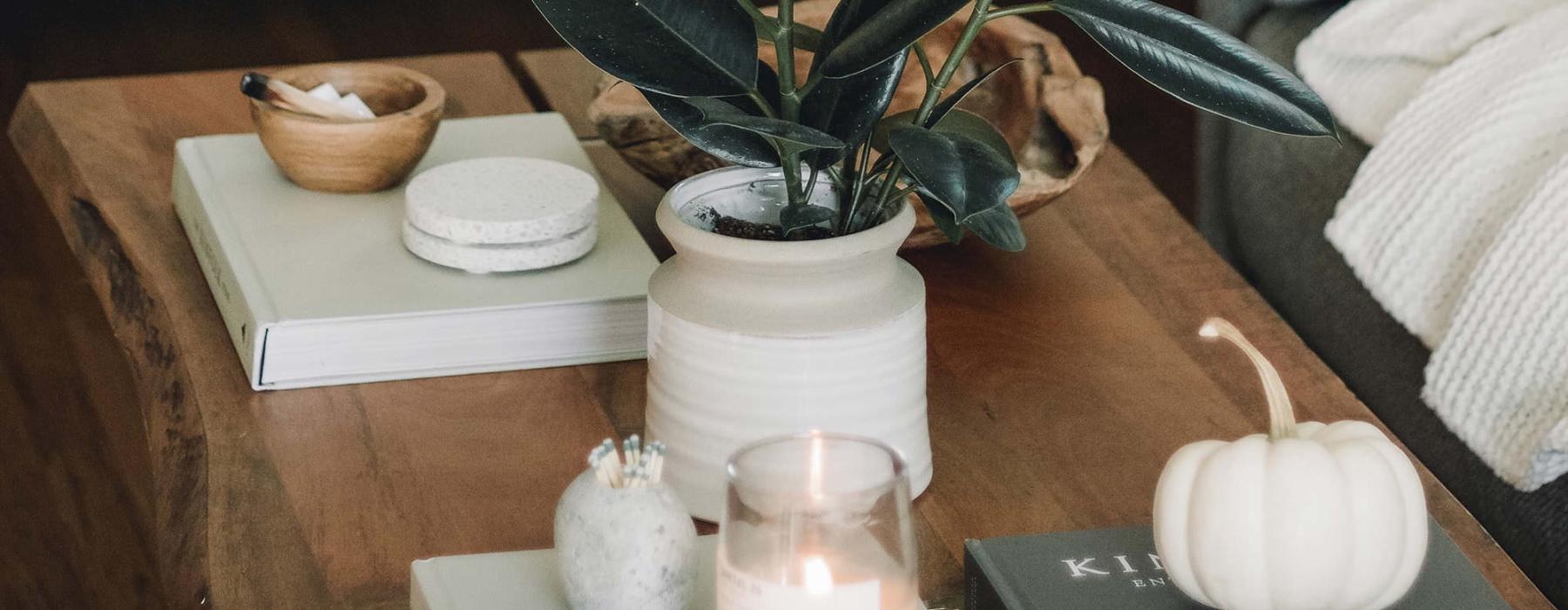 coffee table decorated with books, a potted plant, a candle and other knick-knacks